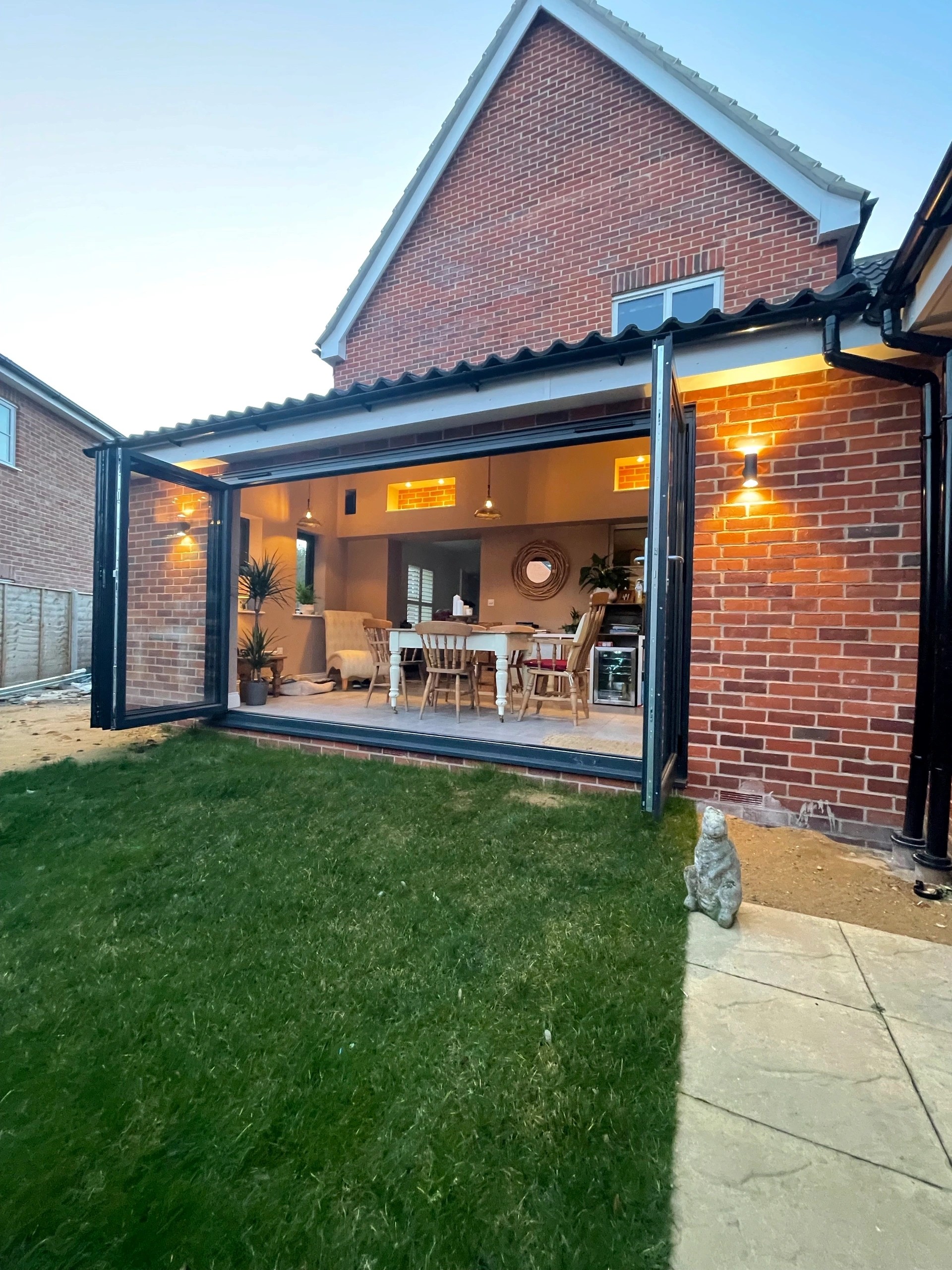 Rear extension in Hunstanton, bi-fold doors open onto the garden with the lit dining space inside