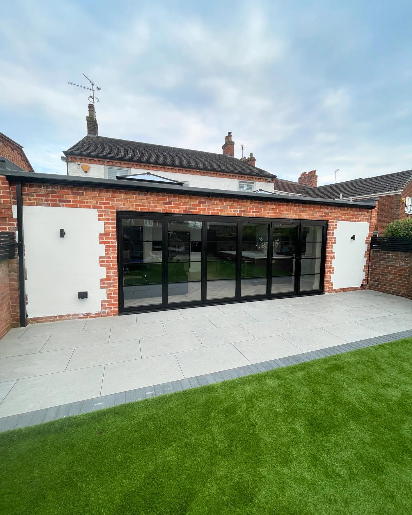 Single storey brick extension with black bifold doors and porcelain patio